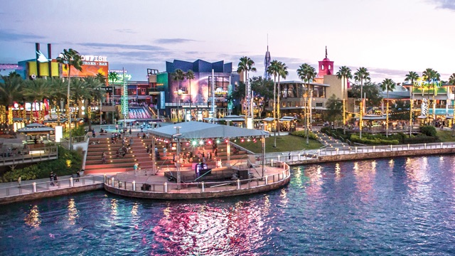 A water taxi cruises along the lagoon in front of a panoramic view of the restaurants, shops and nightclubs of the Universal CityWalk entertainment complex.